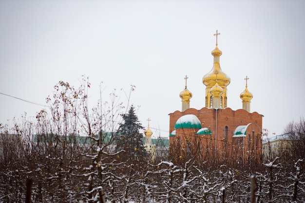 Uma grande igreja ortodoxa no inverno contra o fundo de uma floresta de inverno Cúpulas douradas sob