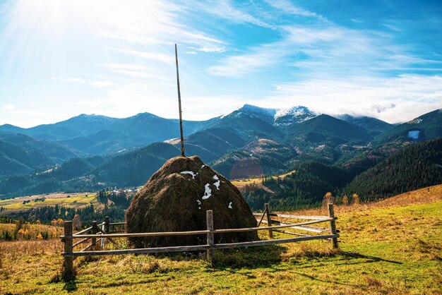 Uma grande pilha de feno seco tendo como pano de fundo a maravilhosa natureza outonal dos Cárpatos e o extraordinário céu azul