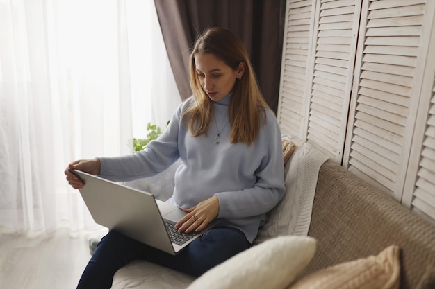 Uma grávida trabalha remotamente em casa. O conceito de freelancer