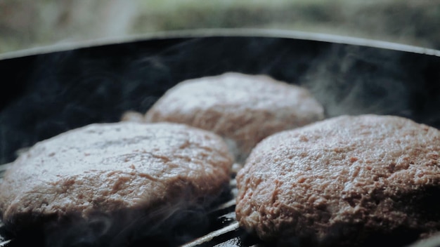 Foto uma grelha com três hambúrgueres cozinhando nela