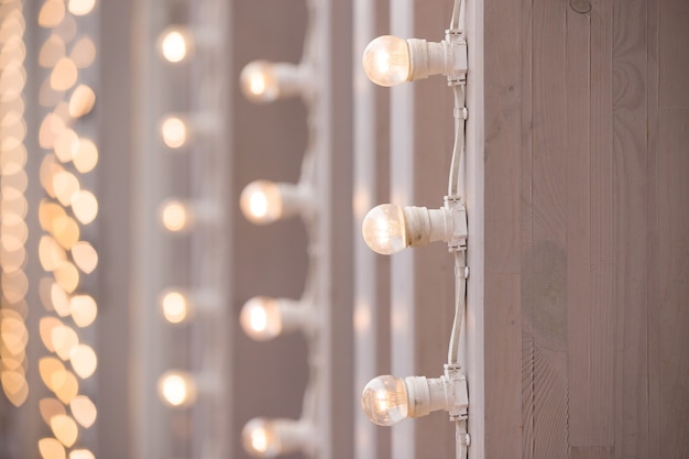 Uma guirlanda acesa de lâmpadas em uma superfície vertical para uma festa de Natal ou casamento