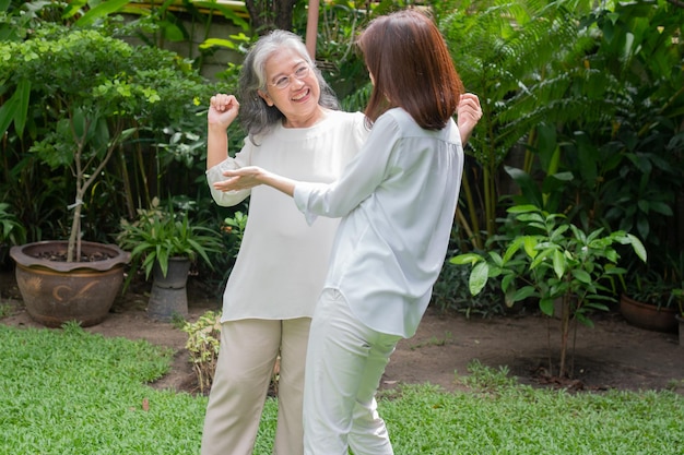 Uma idosa asiática e dança no quintal com sua filha Conceito