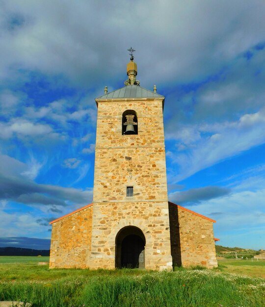 Uma igreja com uma torre sineira e um céu azul atrás dela.