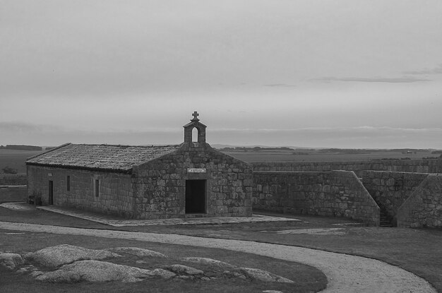 Foto uma igreja no meio de um campo com uma estrada ao fundo.