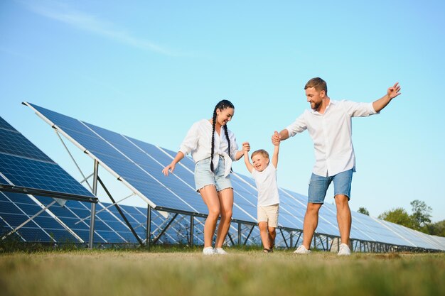 Uma imagem ampla de uma família feliz reunida e sorrindo para a câmera com um grande painel solar no fundo