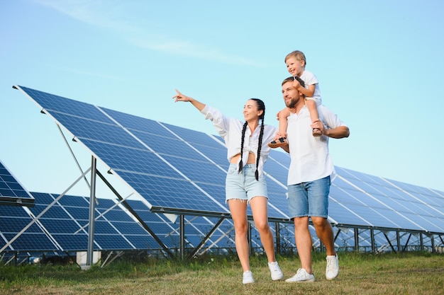 Uma imagem ampla de uma família feliz reunida e sorrindo para a câmera com um grande painel solar no fundo