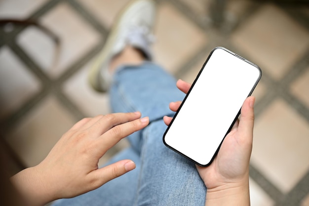 Uma imagem aproximada de uma mulher de jeans sentada do lado de fora e usando seu smartphone