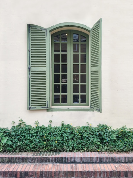 Uma imagem de janela antiga verde e parede branca