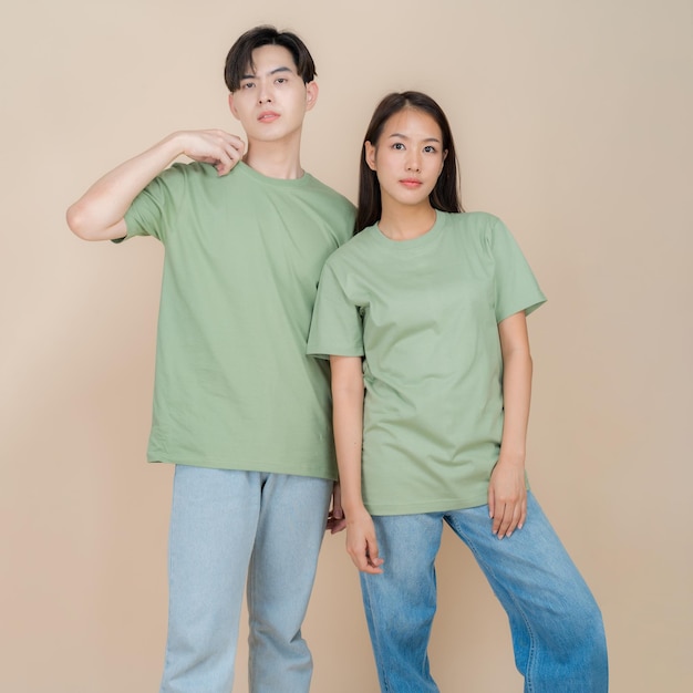 Uma imagem de um modelo de moda masculino e feminino em pé em camiseta verde e jeans em pé no estúdio em fundo bege