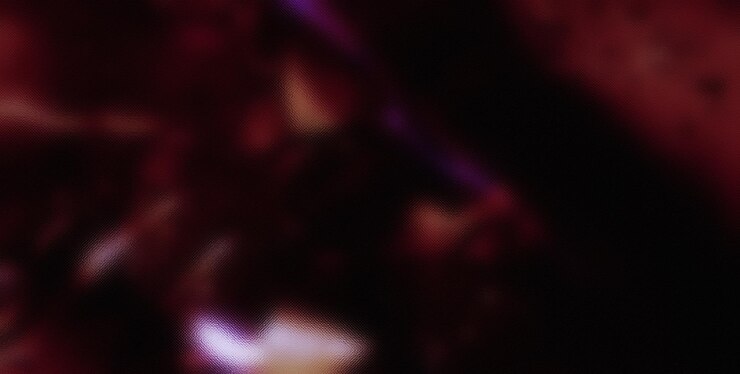 uma imagem desfocada de uma garrafa de vinho vermelho com um fundo roxo