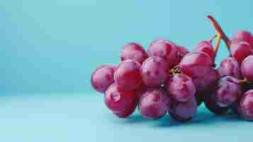 Foto uma imagem em close-up de um feixe de uvas vermelhas maduras com gotas de água em um fundo azul