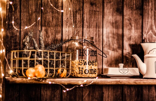 Uma jarra de vidro com flocos de milho e tangerinas em um vaso fica em uma prateleira de madeira decorada com decoração de Natal. foto