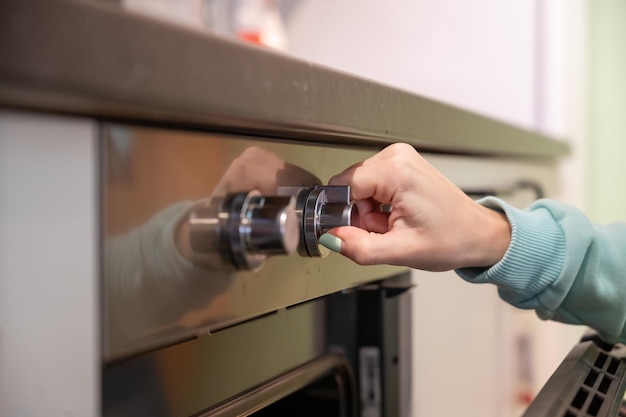 Uma jovem abre o forno A dona de casa inclui um forno embutido A menina está cozinhando bolos