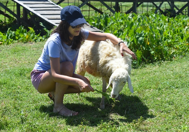 Uma jovem acariciando uma ovelha na fazenda vietnamita