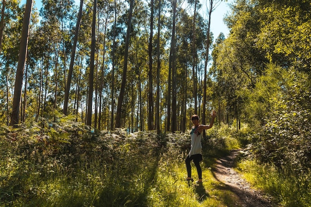 Uma jovem acenando no caminho entre árvores no Parque Natural de Listorreta