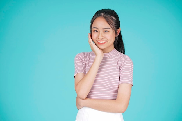 Uma jovem adolescente asiática bonita e atraente com sorriso feliz, belos cuidados com a pele em fundo de cor ciano