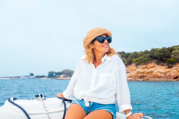 Uma jovem adulta serena sentada em um barco desfrutando de uma excursão costeira durante as férias de verão Ilha no fundo Conceito de viagem e liberdade estilo de vida pessoas no mar