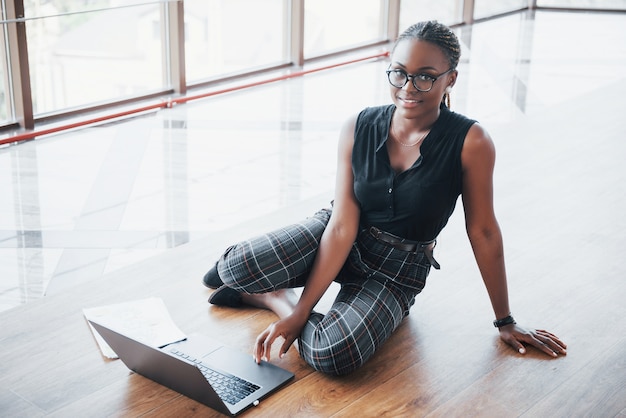 Uma jovem afro-americana está feliz com um laptop.