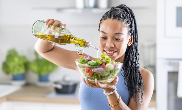 Foto uma jovem afro-americana prepara uma salada de folhas saudável misturada com azeite