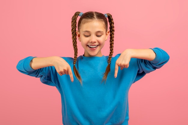 Foto uma jovem alegre com duas longas colas trançadas está vestindo uma camisola azul brilhante ela está de pé