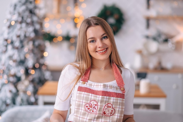 Uma jovem alegre de avental está envolvida em cozinhar em casa se preparando para o feriado