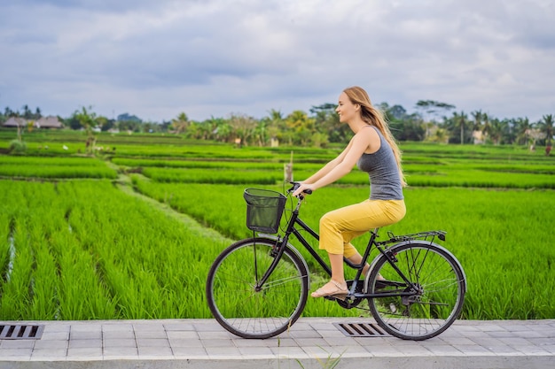 Uma jovem anda de bicicleta em um campo de arroz em ubud bali bali travel concept