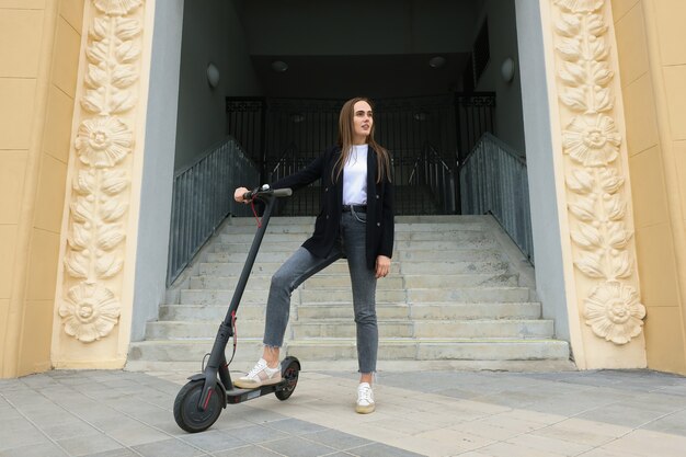 Uma jovem anda de scooter elétrica na cidade. Transporte ecológico