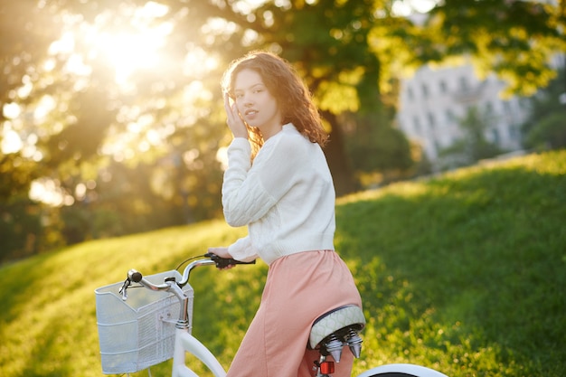 Uma jovem andando de bicicleta ao sol no parque