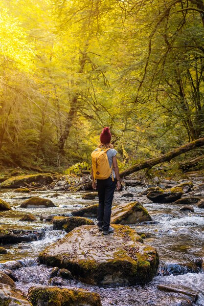 Uma jovem ao pôr do sol no rio no caminho para a ponte suspensa Holtzarte, Larrau. Na floresta ou selva de Irati, Pirineus Atlânticos da França