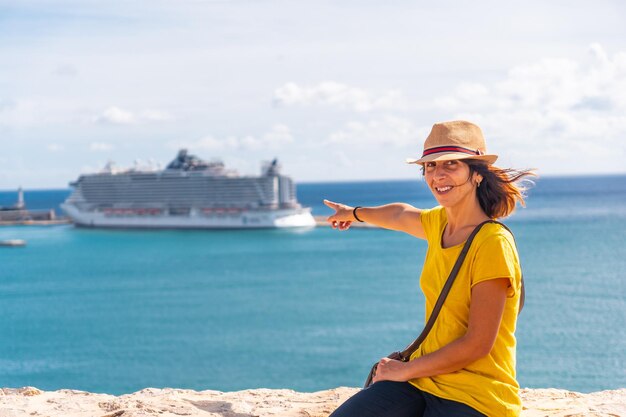 Uma jovem apontando no navio de cruzeiro que chegou à ilha de Ibiza para passar as férias