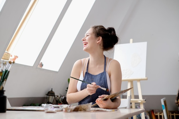 Uma jovem artista pinta um quadro com óleo em tela em um estúdio de arte