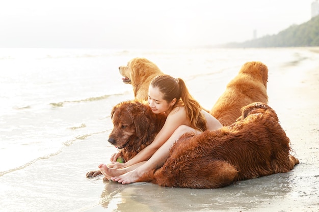 Uma jovem asiática brinca e hud com seu cachorro na praia Conceito de estilo de vida ativo e saudável Relaxamento com um animal de estimação