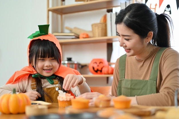 Uma jovem asiática brincalhona e fofa em traje de Halloween gosta de fazer um cupcake de Halloween