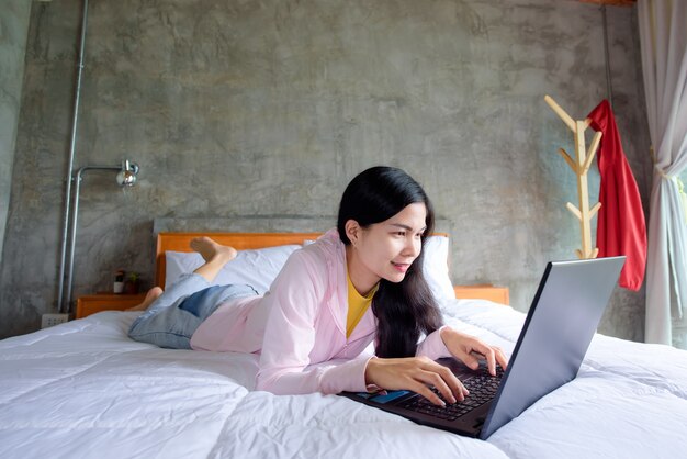 Uma jovem asiática está feliz e revigorada em sua cama.