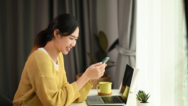 Uma jovem asiática está usando um celular, navegando, navegando na internet sem fio no escritório