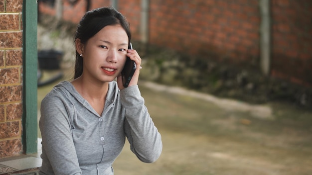 Uma jovem asiática falando ao telefone com um retrato sorridente em chamadas on-line ao ar livre, discutindo e conceito de mídia social, espaço de cópia para texto individual