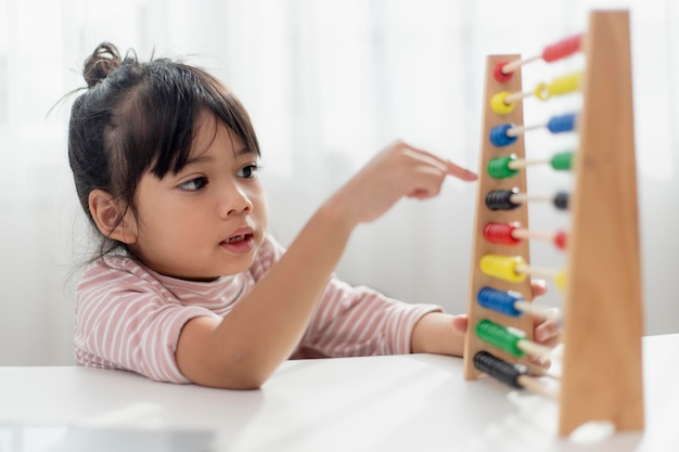 Uma jovem asiática fofa está usando o ábaco com contas coloridas para aprender a contar em casa