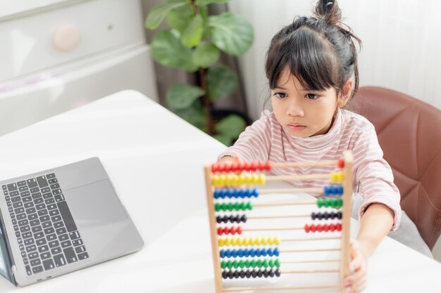 Uma jovem asiática fofa está usando o ábaco com contas coloridas para aprender a contar em casa