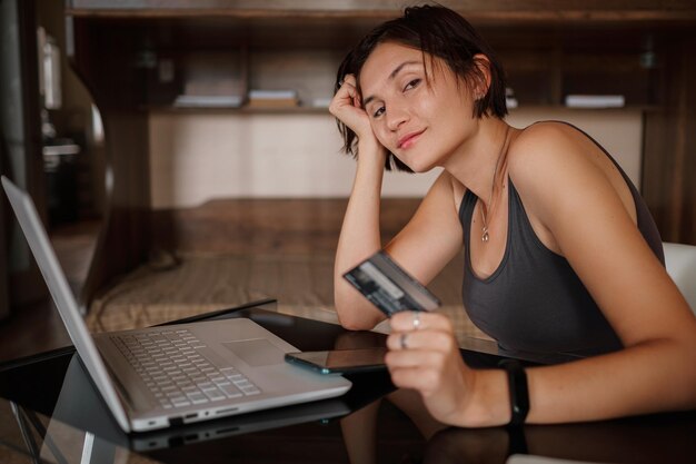 Uma jovem asiática segura um cartão de crédito e usa um laptop