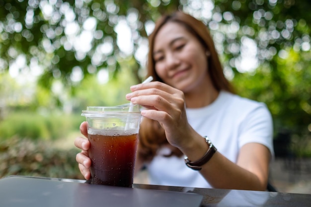 Uma jovem asiática segurando e bebendo café gelado ao ar livre