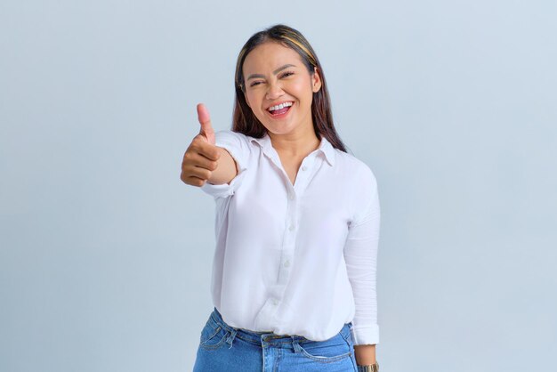 Foto uma jovem asiática sorridente, mostrando o polegar para cima, recomendando algo bom isolado sobre fundo branco