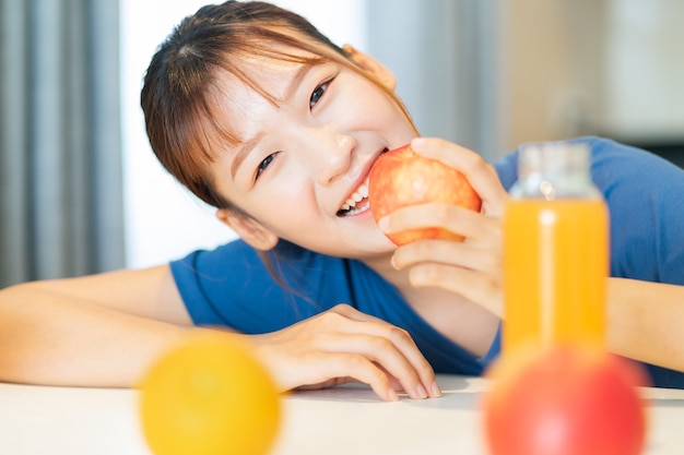 Uma jovem asiática tomando café da manhã com frutas na cozinha