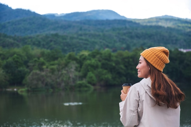 Uma jovem asiática tomando café enquanto viaja pelas montanhas e o lago