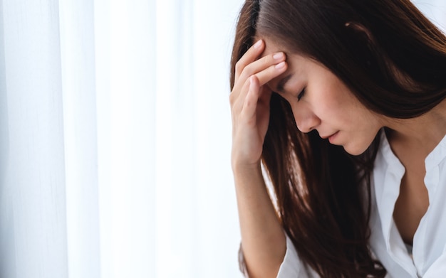 Uma jovem asiática triste e estressada, sentada sozinha no quarto