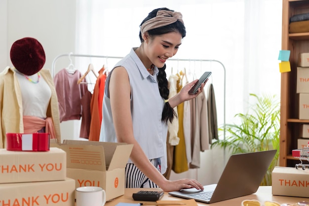 Foto uma jovem asiática vende um empresário de roupas que trabalha em casa, dono de uma pequena empresa
