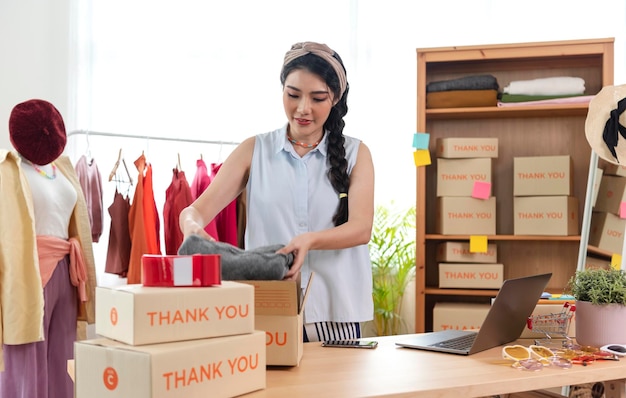 Uma jovem asiática vende um empresário de roupas que trabalha em casa, um pequeno empresário PME