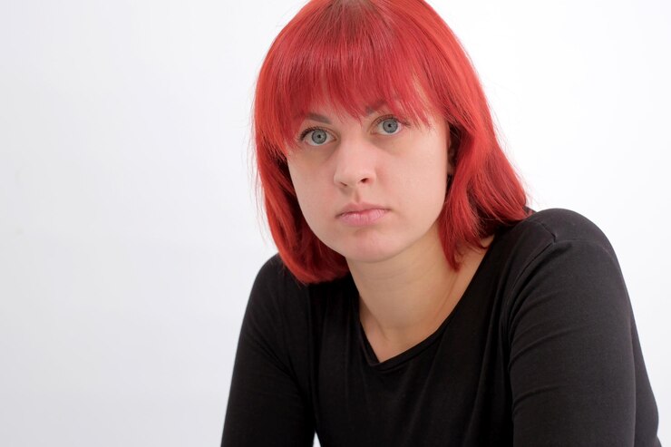 Foto uma jovem atraente com um penteado laranja curto em uma camiseta preta em um fundo branco