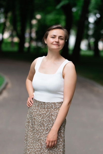 Foto uma jovem atraente em uma blusa branca e saia marrom está no parque de verão