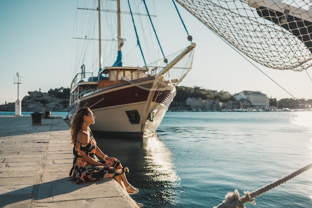 Uma jovem atraente sentada à beira-mar maravilhosa do Mediterrâneo e desfrutando de férias de verão.