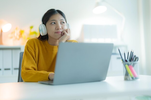 Foto uma jovem atraente usa um computador portátil em seu escritório em casa com fones de ouvido sorrindo